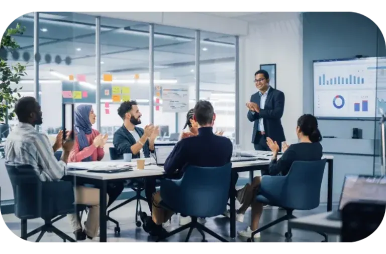 A meeting room applauding a colleague who has just presented a wall of performance dashboards.