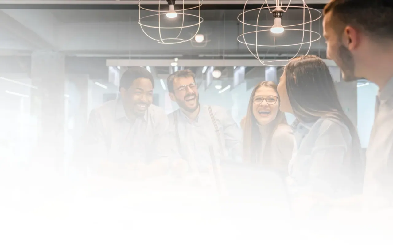 Colleagues laughing together around a table in an open-plan office