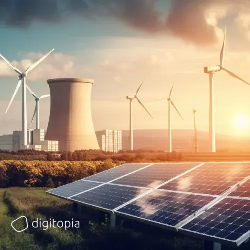 A solar array in the foreground with wind turbines and a power station cooling tower behind it at sunset