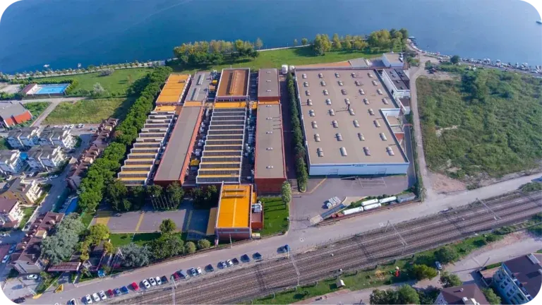Federal Mogul’s plant from the air: long orange-and-grey production halls and a flat-roofed warehouse between the lake shore and the railway line, the town at its edge.