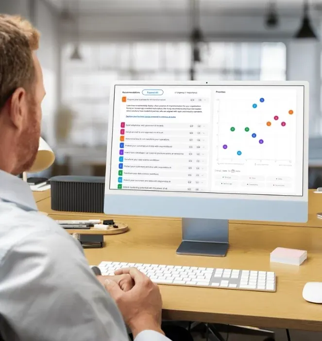 A man reading the assessment’s recommendations and priorities chart on an iMac in an open-plan office.