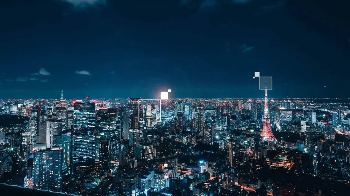 A city skyline at night, lit windows to the horizon, with white outlined squares drawn over two of the towers.
