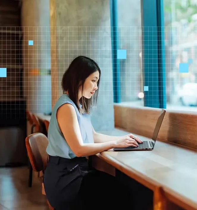 A woman working on a laptop at a café window counter, a grid of pale blue squares drawn over the scene.