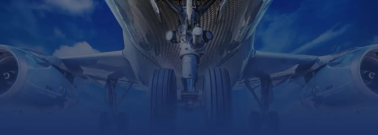 The underside of an airliner on approach, its landing gear and composite fairings in view against a blue sky