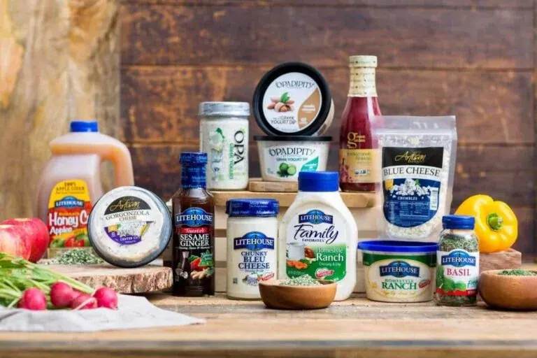 Litehouse Foods’ range on a wooden table: dressings, dips, blue cheese and herbs in jars, tubs and bottles, with apples, radishes and a yellow pepper around them.