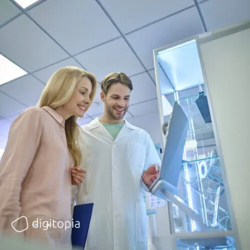A pharmacist and a customer reading a screen together at a dispensing machine