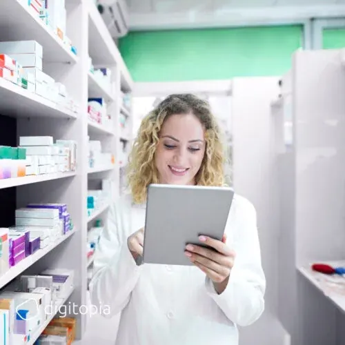A pharmacist holding a tablet in a pharmacy aisle