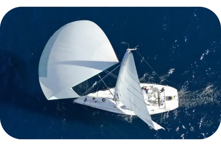 A yacht under full sail on open water, seen from above.
