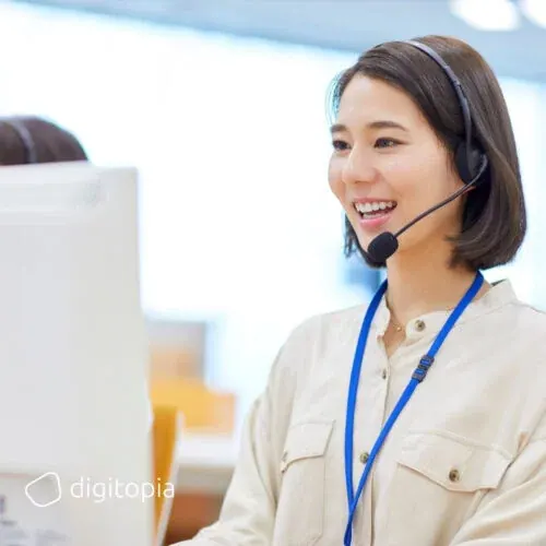 A smiling service agent wearing a headset at her desk