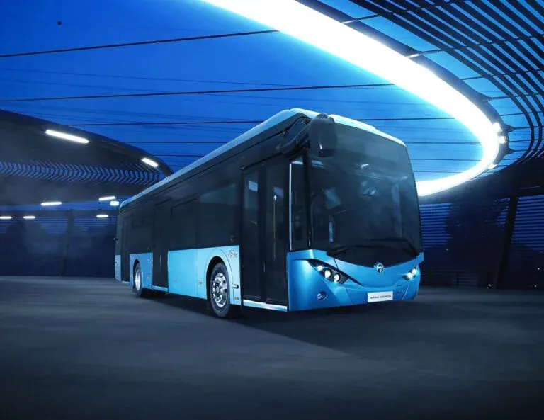 A TEMSA Avenue electron city bus standing under a sweeping arc of blue light.